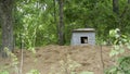 shot of a white watchdog sitting in a kennel in the forest