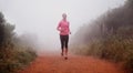 The only way she likes to run. Shot of a woman running on a trail on a misty morning.
