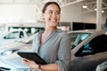 Get ready for the smoothest ride of your life. Shot of a woman using her digital tablet in a car dealership.