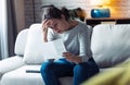 Worried young woman looking at bills and thinking about her problems while sitting on the sofa at home Royalty Free Stock Photo