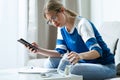 Worried young woman using calculator and looking her savings while sitting on sofa at home Royalty Free Stock Photo