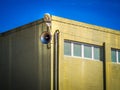 Shot of a yellow building with small windows and speakers outside