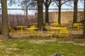 A shot of yellow metal tables and chairs surrounded by autumn colored trees and green and yellow grass near the Mississippi river Royalty Free Stock Photo