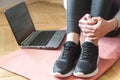Shot of a yound woman at home, ready for follow your online class of yoga. Sneakers close up. Laptop. Home workout concept Royalty Free Stock Photo