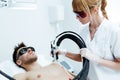 Young beautician removing torso hair with a laser to her client in the beauty salon.