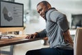 Too many hours in the hot seat. Shot of a young businessman suffering from a backache while working at his desk in his Royalty Free Stock Photo