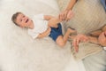 Shot of a young child boy being tickled by his parents while laying down on their bed. Happy childhood concept. Royalty Free Stock Photo