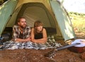 Into the woods. Shot of a young couple lying in a tent looking outwards.