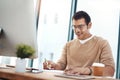 Putting his brilliant ideas to paper. Shot of a young designer writing notes while working at his desk in an office. Royalty Free Stock Photo