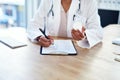 She sends her patients home well equipped for recovery. Shot of a young doctor filling out a form for a prescription in Royalty Free Stock Photo