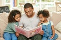 Explore your imagination with a good book. Shot of a young father reading a book with his daughters at home. Royalty Free Stock Photo