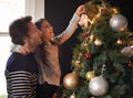 Its a daddy daughter thing. Shot of a young girl and her father decorating the Christmas tree together.