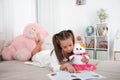 Young girl lying on the sofa  at home and reading a book  with her favorite soft toy Royalty Free Stock Photo