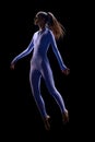 Shot of young incredibly beautiful woman wearing suit jumping in air over dark background. Female body levitation