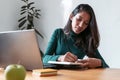 Young indian business woman entrepreneur writing in her agenda while working with laptop in the office Royalty Free Stock Photo