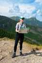 Woman traveler explorer with backpack hiking to the top of the mountain.Shot of a young lost woman holding a map while