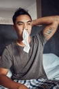 Has anybody seen my tissue. Shot of a young man blowing his nose while recovering from an illness in bed at home. Royalty Free Stock Photo