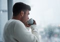 A simple break will bring you back to you. Shot of a young man having coffee and looking out of a window on a rainy day Royalty Free Stock Photo