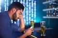 Drunken texts are never a good idea. Shot of a young man looking upset while using his phone at a bar. Royalty Free Stock Photo