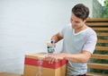 Sealing up the last few boxes. Shot of a young man packing up his belongings into boxes before moving out. Royalty Free Stock Photo