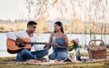 He won her heart all over again. Shot of a young man playing a guitar while on a picnic with his girlfriend at a Royalty Free Stock Photo