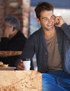 So good to hear from you again. Shot of a young man sitting in a cafe and talking on a cellphone. Royalty Free Stock Photo