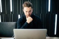 Young man sitting at table looking away and thinking. Thoughtful businessman sitting office.