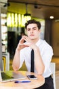 Shot of young man sitting at table looking at camera and thinking. Thoughtful businessman sitting home office. Sales man Royalty Free Stock Photo