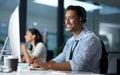 Courtesy and professionalism pays off. Shot of a young man using a headset and computer in a modern office.