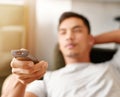 Seeking the sports channel. Shot of a young man using a remote control to change the channel on his television while he Royalty Free Stock Photo