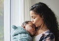 Ill cherish you for life. Shot of a young mother giving her baby a kiss at home.