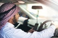 You have reached your destination. Shot of a young muslim businessman using his phone while driving a car. Royalty Free Stock Photo