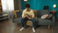 Shot of a young redhead woman sittingon the couch in a room with a smartphone in her hands. She looks calm and relaxed.