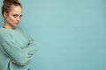 Shot of young sad upset dissatisfied angry pretty blonde woman wearing blue jersey isolated on blue background with