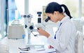 The closer she looks, the closer the answer. Shot of a young scientist using a microscope in a laboratory. Royalty Free Stock Photo