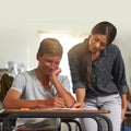 Showing him how its done. Shot of a young teacher explaining something to a student in her class. Royalty Free Stock Photo