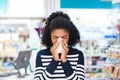 Got the flu Weve got just the remedy for you. Shot of a young woman blowing her nose in a pharmacy.