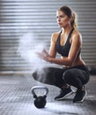 Ready to start lifting. Shot of a young woman coating her hands with sports chalk before a kettle bell workout.