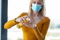 Young woman with hygienic mask applying a sanitizing gel liquid for cleaning her hands. Prevention at home