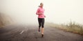 The miles are rolling away behind her. Shot of a young woman jogging on a country road on a misty morning. Royalty Free Stock Photo