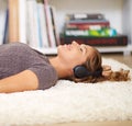 Music soothes the soul. Shot of a young woman listening to music while relaxing at home.