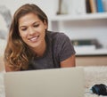 Catching up on her personal emails. Shot of a young woman relaxing at home with her laptop.