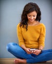 Sharing the happiness thanks to technology. Shot of a young woman sitting on the floor and using her mobile phone. Royalty Free Stock Photo