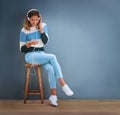 One on one time with her favourite music. Shot of a young woman sitting on a stool and listening to music. Royalty Free Stock Photo