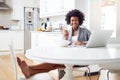 This is what Saturday morning looks like. Shot of a young woman surfing the net while enjoying breakfast in her kitchen Royalty Free Stock Photo