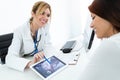 Young woman gynecologist doctor showing to pregnant woman ultrasound scan baby with digital tablet in medical consultation Royalty Free Stock Photo