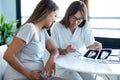 Young woman gynecologist doctor showing to pregnant woman ultrasound scan baby in medical consultation Royalty Free Stock Photo