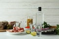 Shots of vodka and tasty snacks on white wooden background Royalty Free Stock Photo