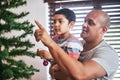That should go near the top. a cheerful young man and his son putting up Christmas decorations on a tree at home during Royalty Free Stock Photo