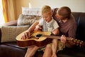 Should we play your favourite tune. a father and his little son playing the guitar together at home. Royalty Free Stock Photo